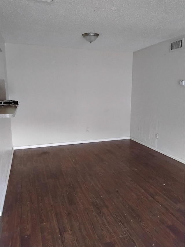 empty room with dark wood-type flooring and a textured ceiling