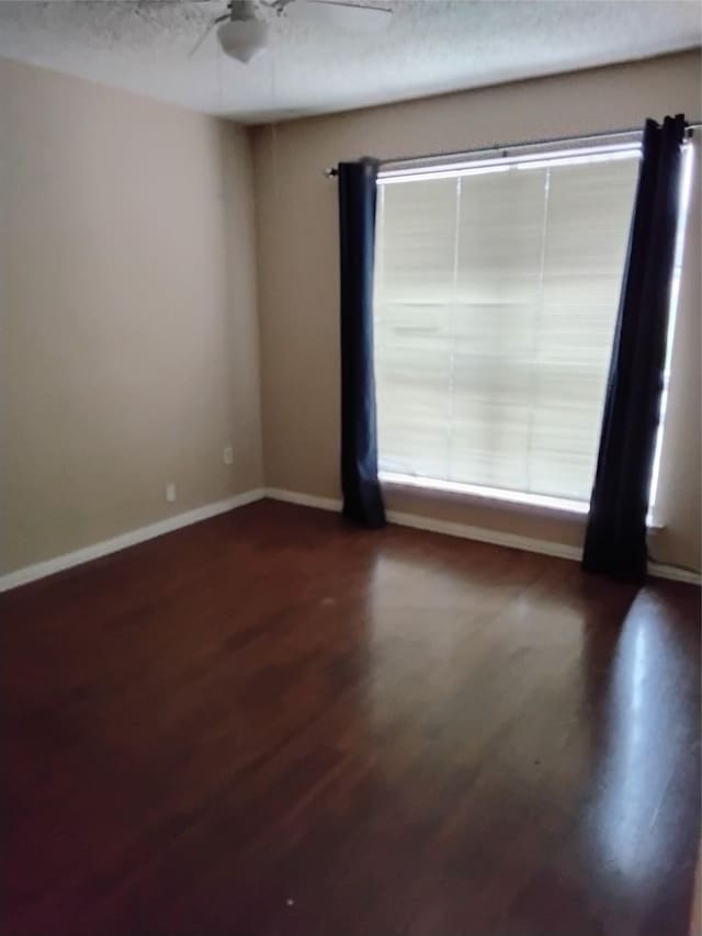 empty room featuring dark hardwood / wood-style flooring, a textured ceiling, and ceiling fan