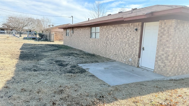 view of home's exterior featuring a trampoline, a playground, a patio, and a lawn