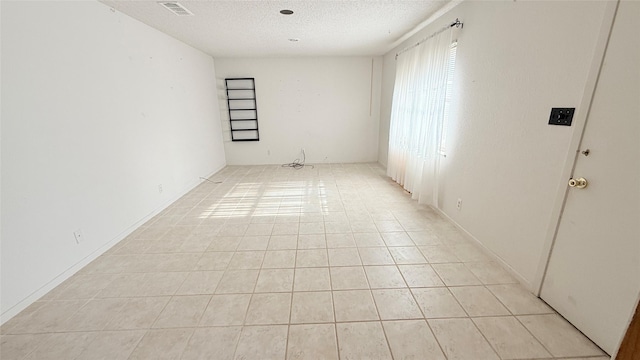 tiled spare room with a textured ceiling