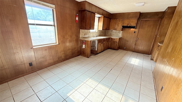 kitchen with sink, light tile patterned floors, a textured ceiling, and wood walls