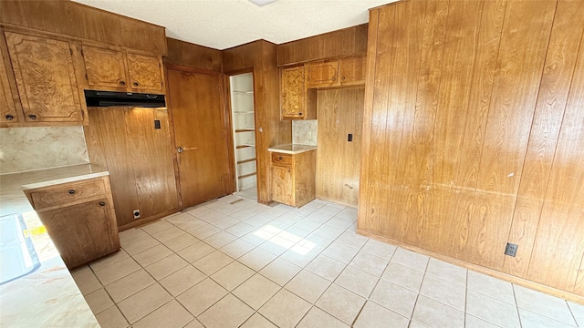 kitchen with light tile patterned floors and wood walls