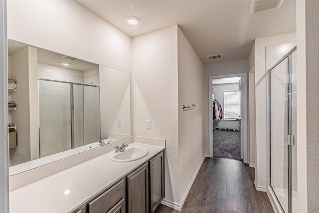 bathroom featuring wood-type flooring, vanity, and a shower with shower door