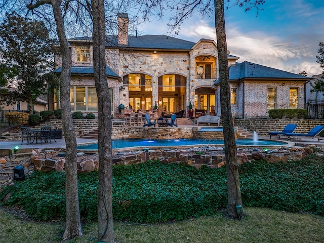 45 Dunrobin, Richardson, TX 75082 - back of property at dusk with a chimney, a patio area, french doors, a balcony, and brick siding