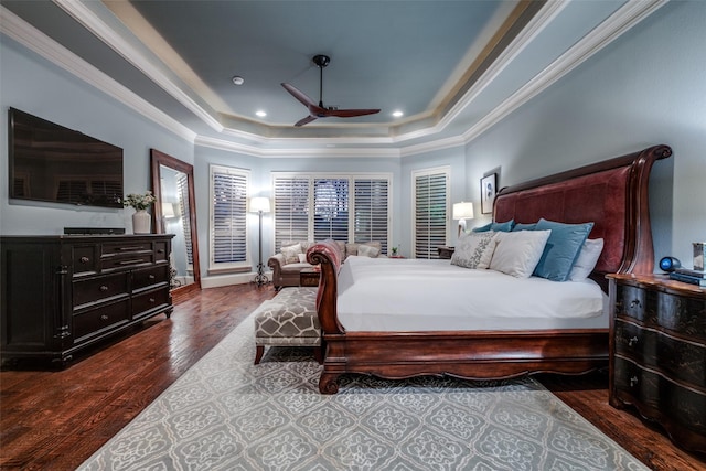 bedroom with wood finished floors, ceiling fan, ornamental molding, and a tray ceiling