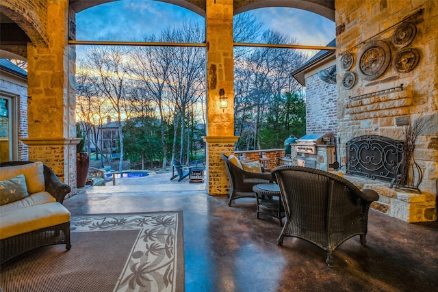 living area featuring finished concrete floors, plenty of natural light, an outdoor stone fireplace, and a high ceiling