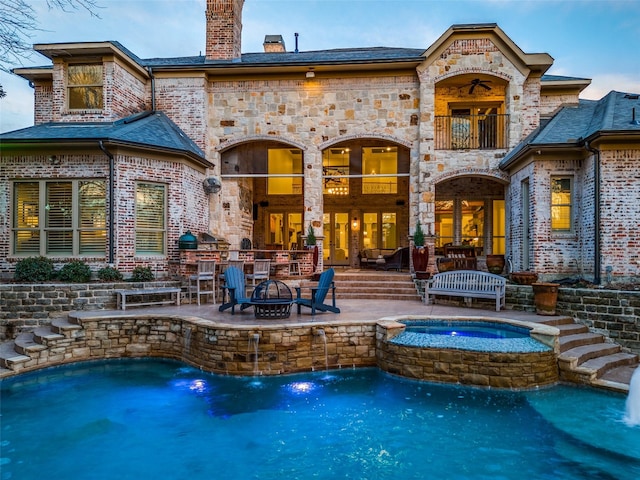 back of house with a patio, an outdoor fire pit, pool water feature, and a swimming pool with hot tub