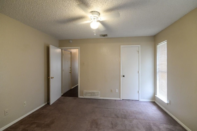 unfurnished bedroom with ceiling fan, a textured ceiling, and dark colored carpet