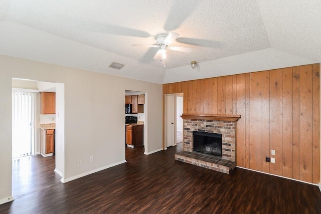 unfurnished living room featuring ceiling fan, lofted ceiling, dark wood-type flooring, and a fireplace