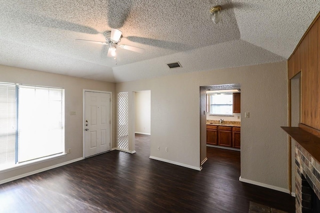 interior space with lofted ceiling, sink, dark wood-type flooring, ceiling fan, and a textured ceiling