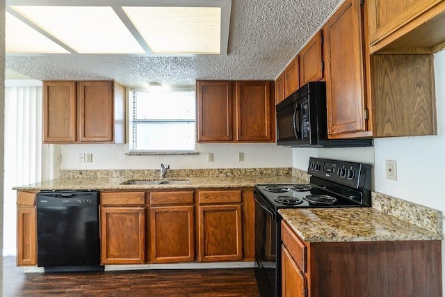 kitchen with sink, dark hardwood / wood-style flooring, black appliances, light stone countertops, and a textured ceiling