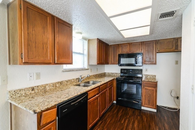 kitchen with sink, a textured ceiling, dark hardwood / wood-style floors, light stone countertops, and black appliances