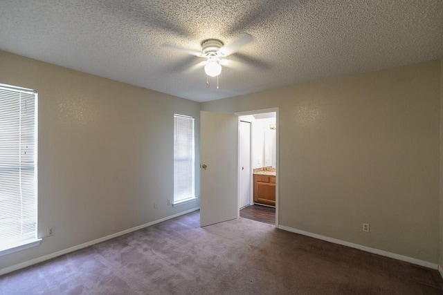 unfurnished bedroom featuring ceiling fan, connected bathroom, a textured ceiling, and dark colored carpet