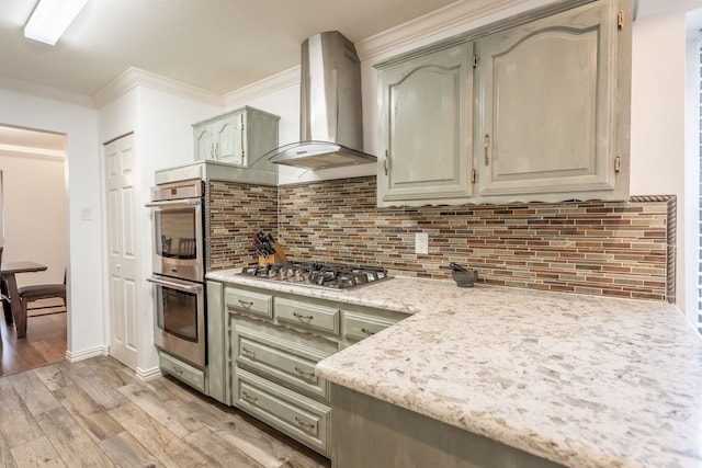 kitchen with appliances with stainless steel finishes, range hood, tasteful backsplash, ornamental molding, and light hardwood / wood-style floors