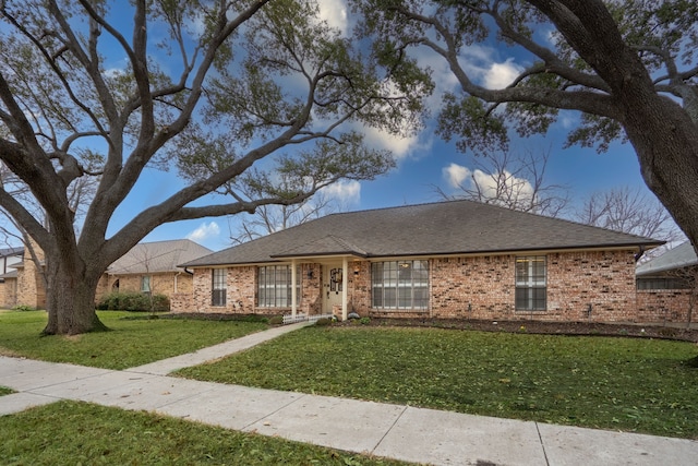 ranch-style house with a shingled roof, a front yard, and brick siding