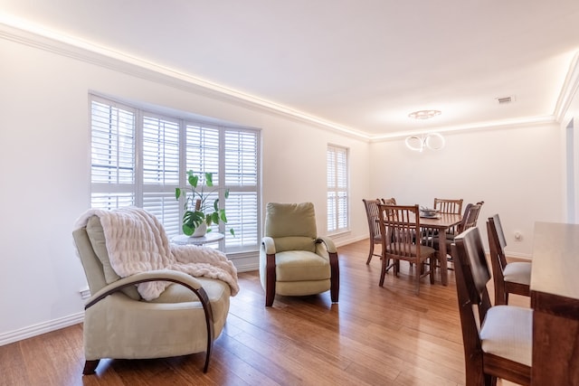 living area with crown molding, hardwood / wood-style floors, and a chandelier