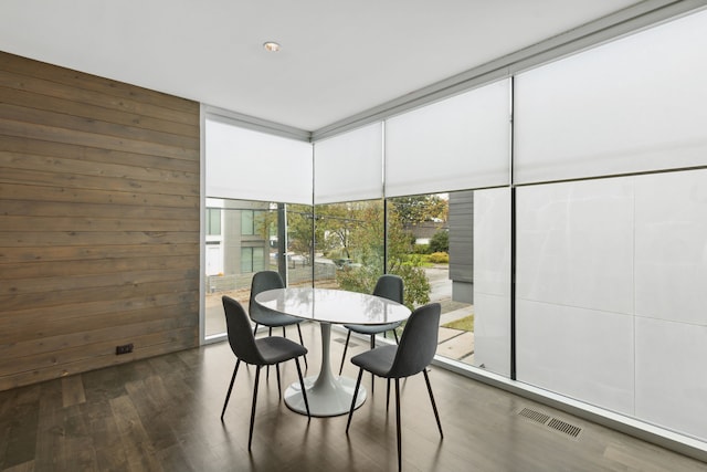 dining room featuring floor to ceiling windows, dark hardwood / wood-style floors, and wood walls