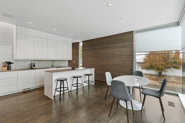 dining room with sink, floor to ceiling windows, dark hardwood / wood-style floors, and wood walls