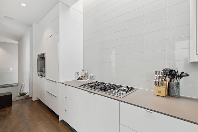 kitchen with white cabinetry, stainless steel appliances, dark wood-type flooring, and decorative backsplash