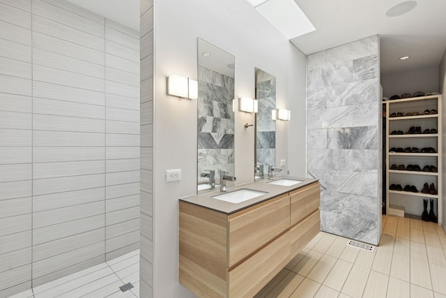 bathroom with tile patterned floors, vanity, tile walls, and a shower