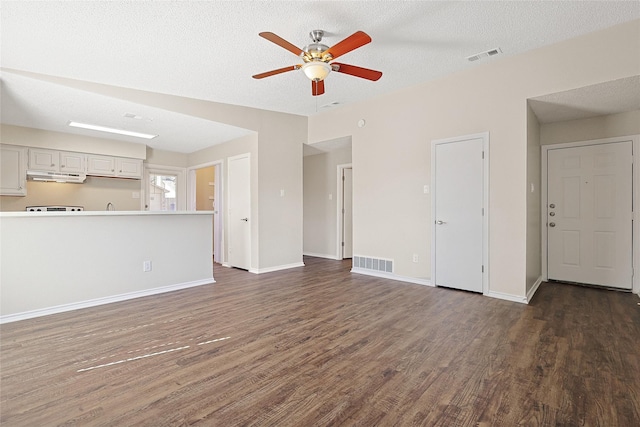 unfurnished living room with dark hardwood / wood-style flooring, ceiling fan, and a textured ceiling