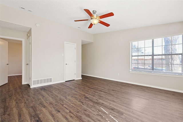 empty room with ceiling fan, dark hardwood / wood-style floors, and a textured ceiling