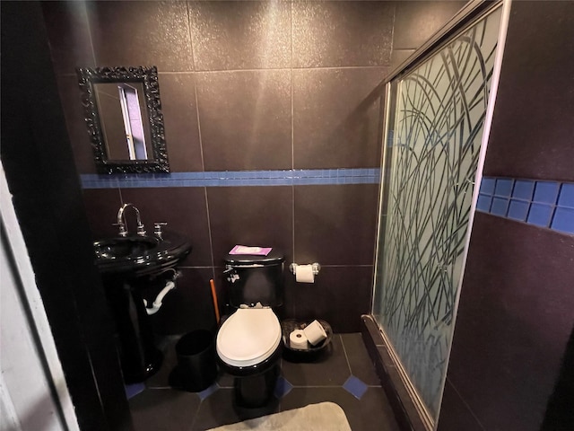 bathroom with tile walls, sink, tile patterned flooring, and toilet