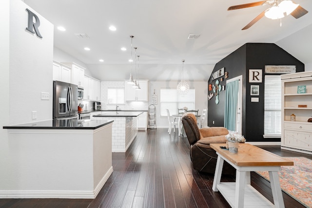 kitchen with lofted ceiling, white cabinetry, hanging light fixtures, appliances with stainless steel finishes, and dark hardwood / wood-style flooring