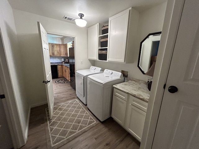 washroom featuring cabinets, dark hardwood / wood-style floors, and washer and clothes dryer