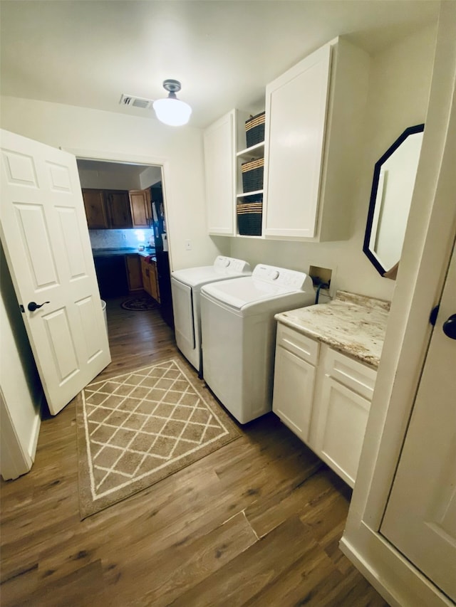 clothes washing area with cabinets, dark hardwood / wood-style flooring, and washing machine and dryer