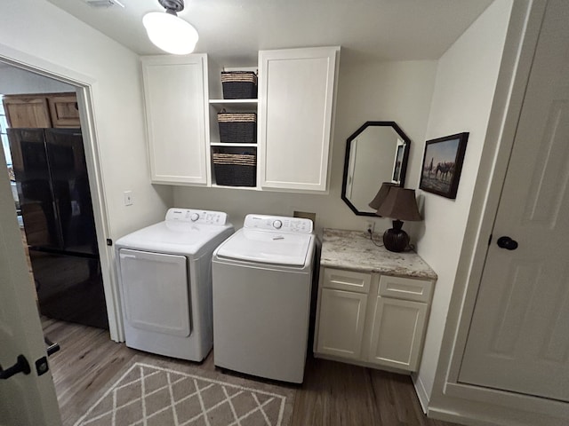 laundry area featuring cabinets, light hardwood / wood-style flooring, and washing machine and clothes dryer