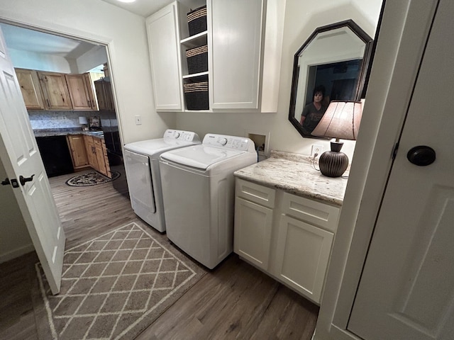 laundry room featuring dark hardwood / wood-style flooring, washing machine and dryer, and cabinets