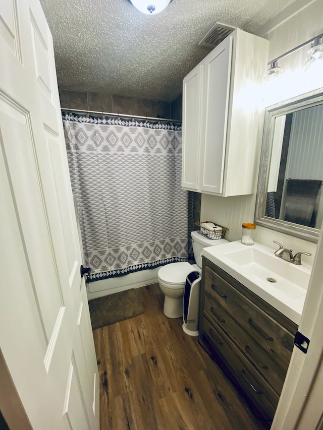 bathroom featuring wood-type flooring, toilet, a textured ceiling, and vanity