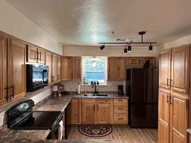 kitchen with hanging light fixtures, sink, light hardwood / wood-style floors, and black appliances