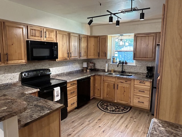 kitchen with sink, backsplash, dark stone counters, black appliances, and light wood-type flooring