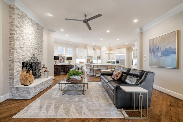 living room featuring hardwood / wood-style flooring, ceiling fan with notable chandelier, and ornamental molding