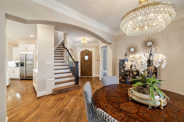 dining area featuring hardwood / wood-style flooring, ornamental molding, and an inviting chandelier