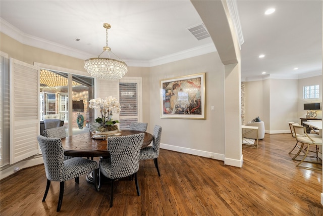 dining room with hardwood / wood-style flooring, crown molding, and a chandelier