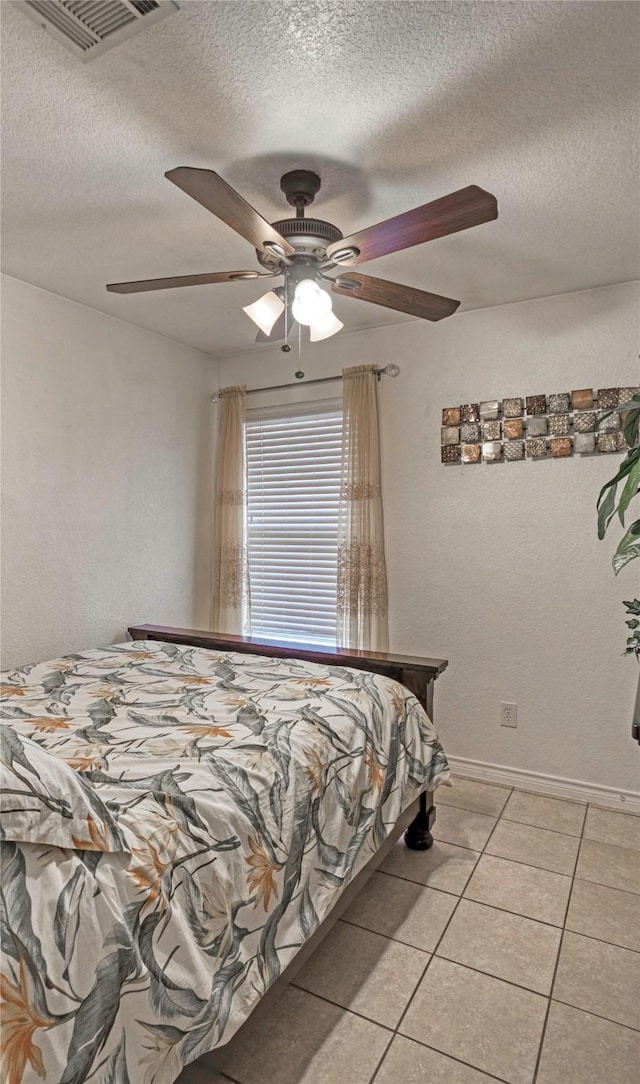 bedroom with ceiling fan, a textured ceiling, and light tile patterned floors