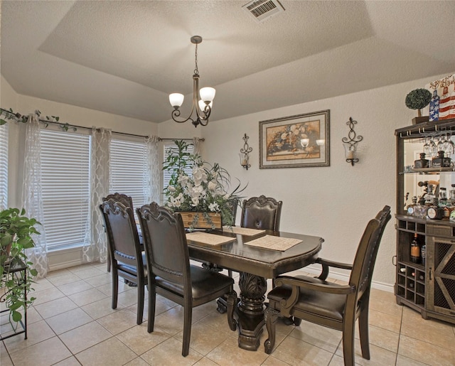 dining area featuring a notable chandelier, vaulted ceiling, a raised ceiling, and a textured ceiling