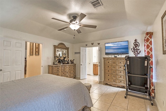 bedroom featuring light tile patterned flooring, connected bathroom, ceiling fan, and a textured ceiling