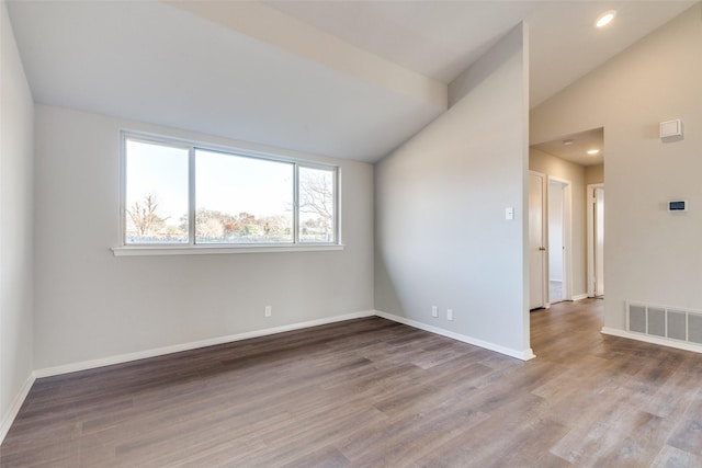 unfurnished room featuring hardwood / wood-style flooring and lofted ceiling