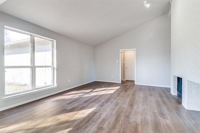 unfurnished living room featuring a fireplace, high vaulted ceiling, and light wood-type flooring