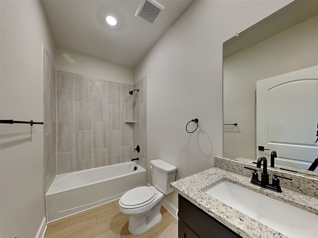 full bathroom with hardwood / wood-style flooring, tiled shower / bath, vanity, and toilet