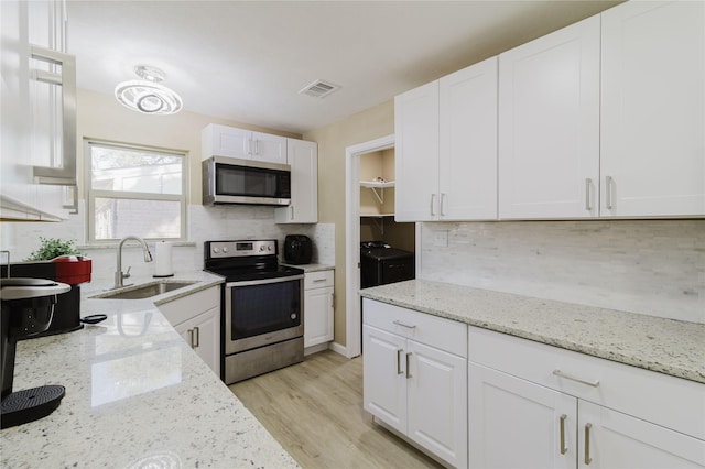 kitchen with white cabinetry, appliances with stainless steel finishes, sink, and light stone counters