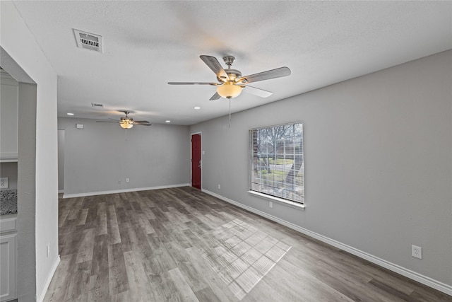 empty room with hardwood / wood-style flooring, ceiling fan, and a textured ceiling