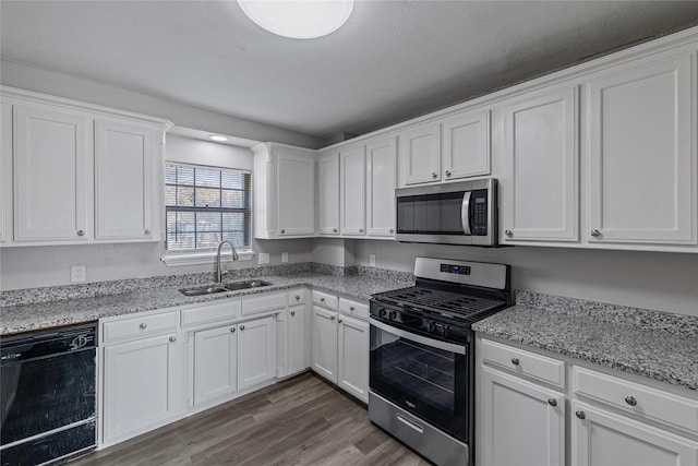 kitchen featuring dark hardwood / wood-style floors, white cabinetry, sink, stainless steel appliances, and light stone countertops