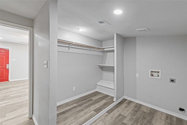 laundry area with washer hookup, hookup for an electric dryer, light hardwood / wood-style flooring, and a textured ceiling