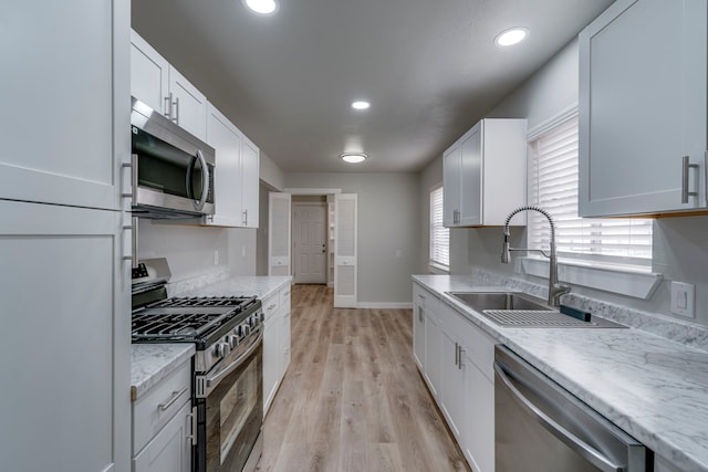 kitchen featuring stainless steel appliances, white cabinetry, and sink