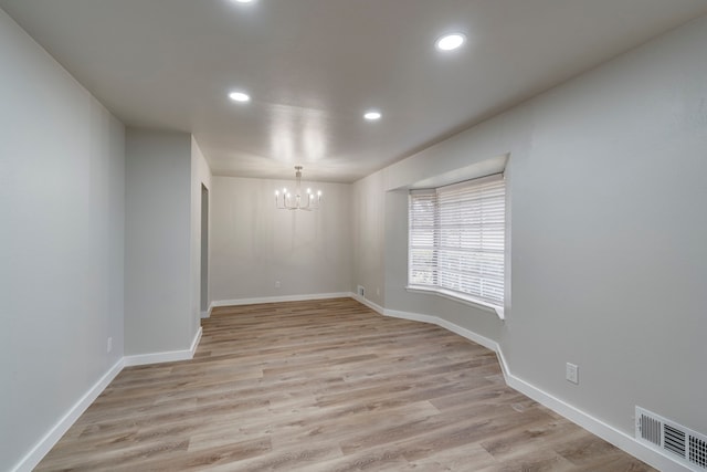 unfurnished room with a chandelier and light hardwood / wood-style floors